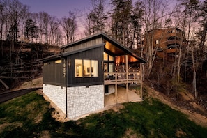 Eine moderne Hütte mit Balkon, umgeben von Bäumen.