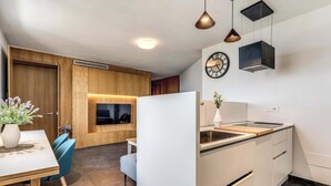 A modern kitchen with a built-in oven, a dining area with a table and chairs, and a clock on the wall. - Sea View Suite Priora with Private Terrace (Priora)