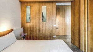 A hotel room with a wooden accent wall, a bed with white linens, and a small vase with flowers. - Sea View Suite Priora with Private Terrace (Priora)