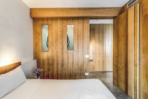 A hotel room with a wooden accent wall, a bed with white linens, and a small vase with flowers. - Sea View Suite Priora with Private Terrace (Priora)