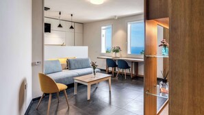 A modern living room with a sofa, a coffee table, and a dining area with chairs. - Sea View Suite Priora with Private Terrace (Priora)