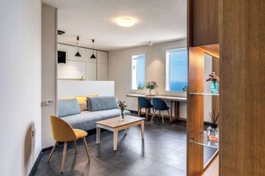A modern living room with a sofa, a coffee table, and a dining area with chairs. - Sea View Suite Priora with Private Terrace (Priora)