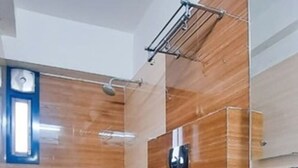 Un baño moderno con piso de madera, un inodoro blanco, un lavabo con espejo y una zona de ducha.