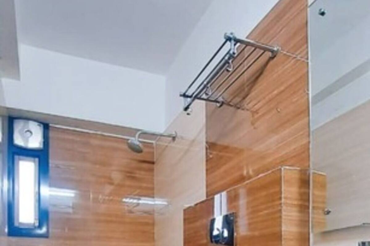 Un baño moderno con piso de madera, un inodoro blanco, un lavabo con espejo y una zona de ducha.