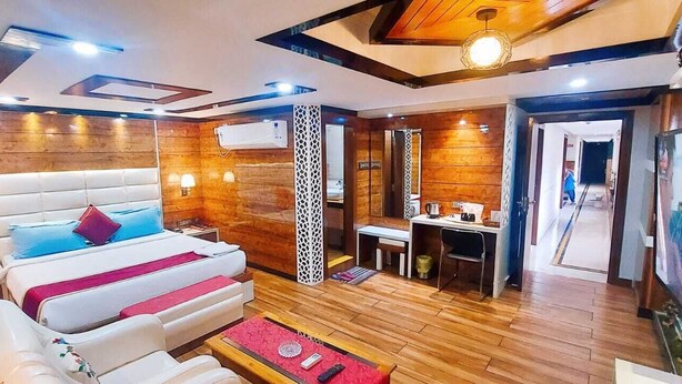 Habitación de hotel con una cama grande, un escritorio, una silla y un televisor.