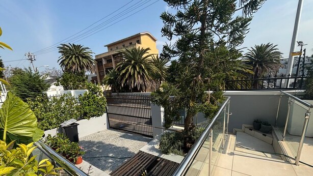 A rooftop terrace with a metal railing, potted plants, and a gated entrance. - Herbert House (Cape Town)