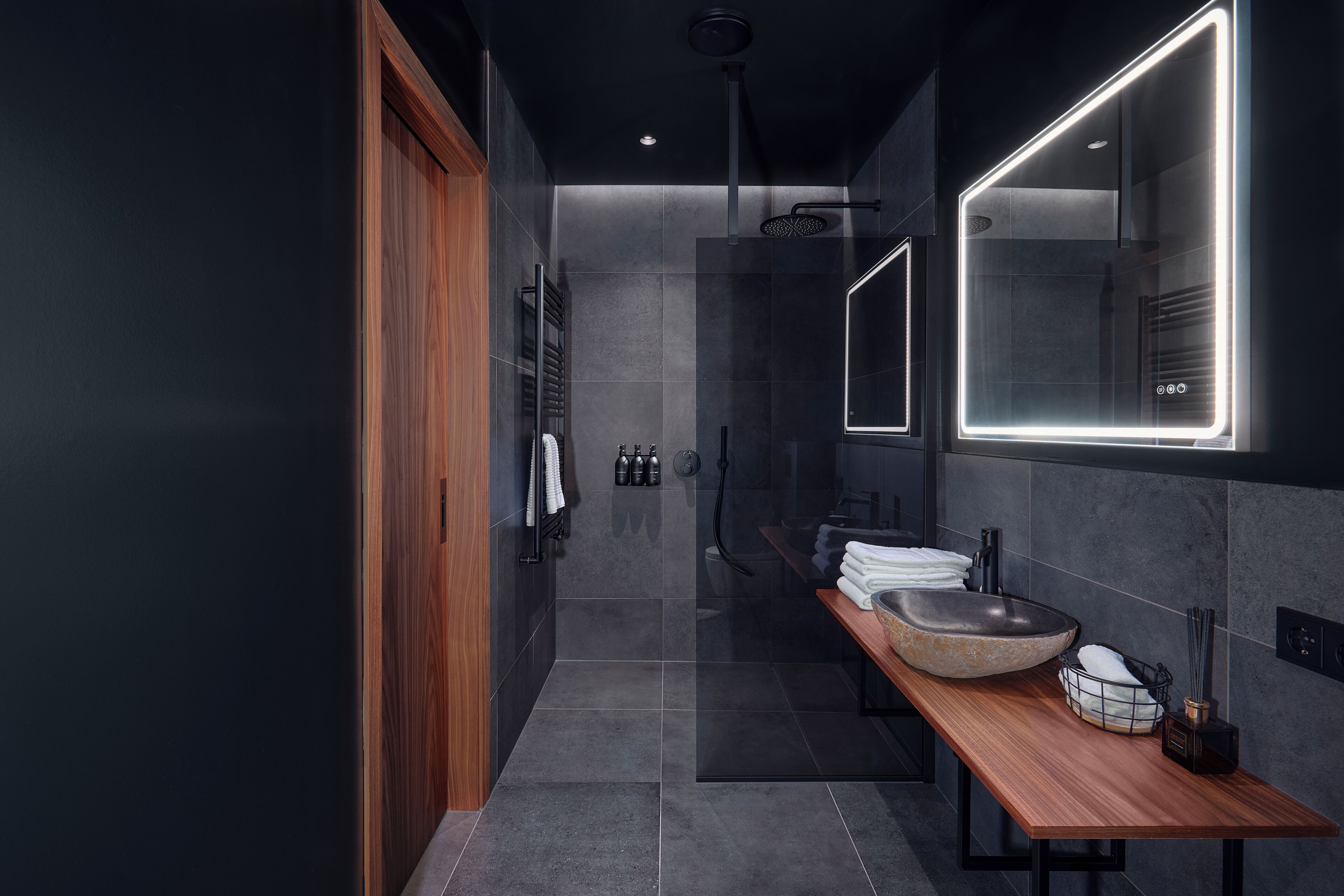 Un baño moderno con tocador de madera, un espejo grande y un lavabo empotrado.