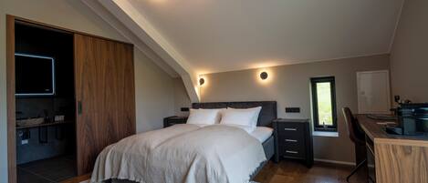 A bedroom with a bed, bedside tables, a desk, a window, and a built-in wardrobe.
