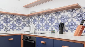 Una cocina con armarios azules, lavavajillas, cafetera y bloque de cuchillos.