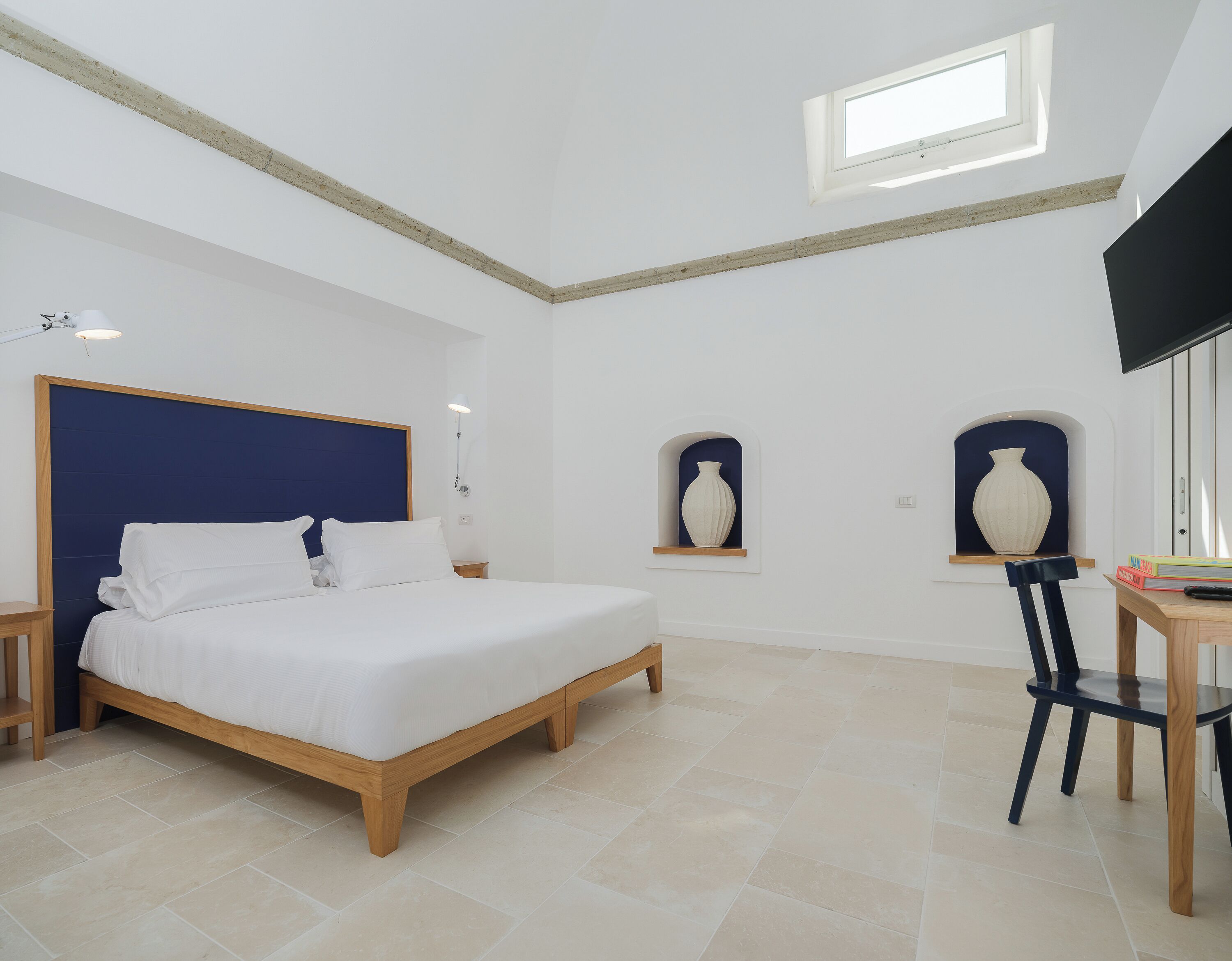 Une chambre à coucher comprenant un lit, des tables de chevet, un bureau, une chaise et deux vases fixés au mur.