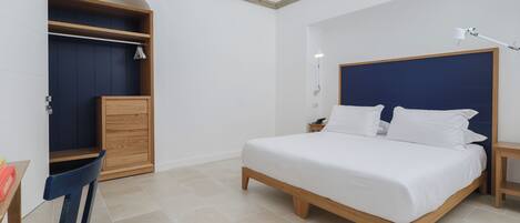 Un dormitorio con cama, armario de madera y escritorio con silla.