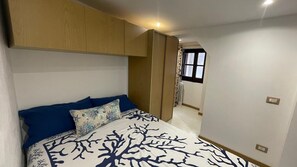 A bedroom with a bed, a wardrobe, and a window. - Romantic Cefalù - Studio Apartment in the Heart of the Historic Center (Cefalù)