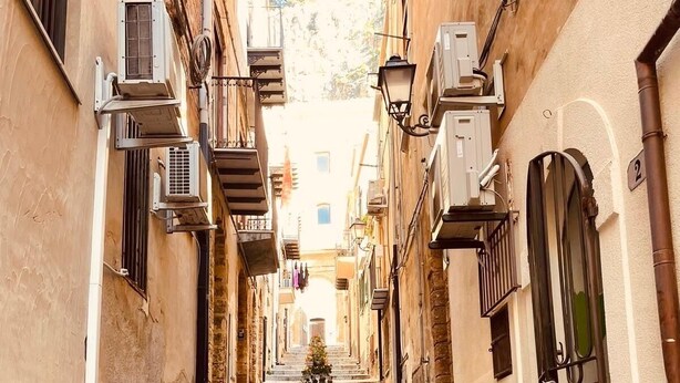 Una calle estrecha con escalones de piedra, edificios tradicionales y macetas al aire libre.