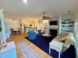 A living room with a fireplace, a dining area, and a kitchen.