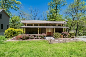 A two-story house with a porch, surrounded by well-maintained landscaping and trees. - Newly Remodeled Cabin with Lake Views & Grill Patio in Rogers, Arkansas (Rogers)