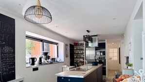 A modern kitchen with a large island, a coffee machine, and a chalkboard menu. - Air-conditioned family home with a pool near Lyon (Sathonay-Camp)