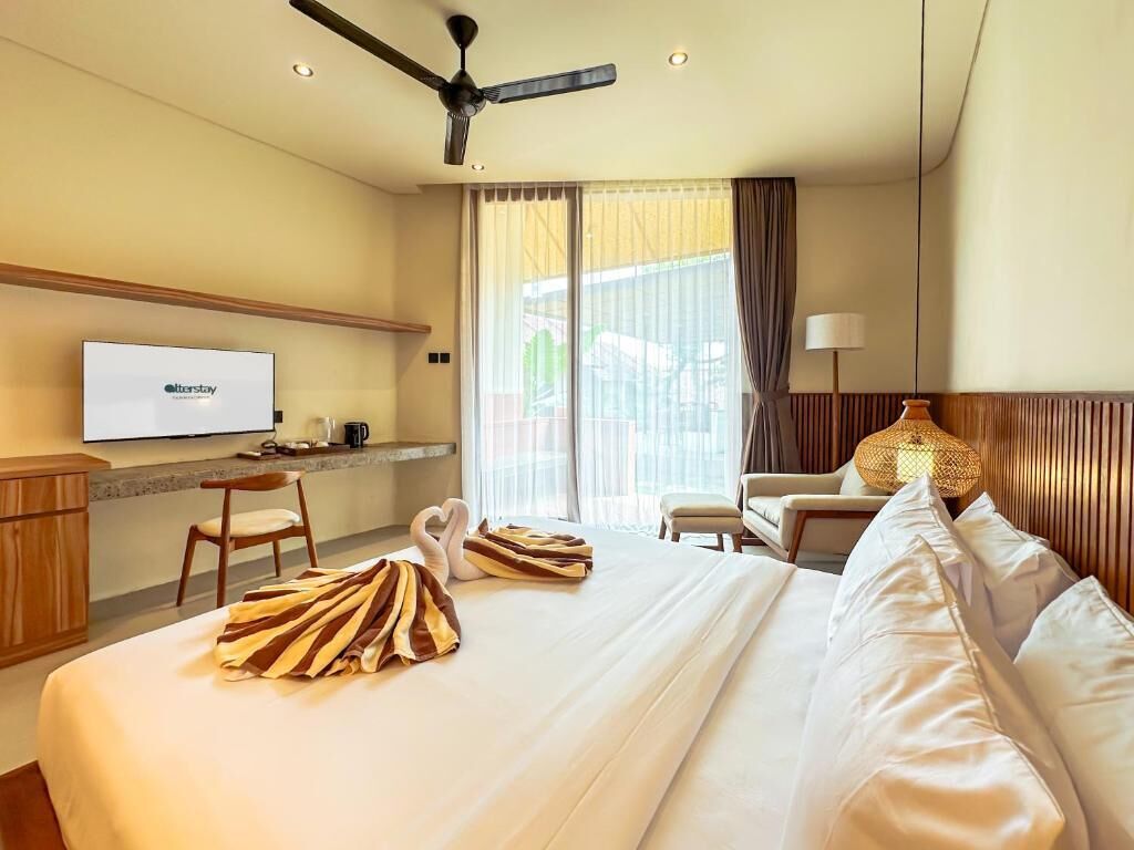 Une chambre d’hôtel avec un lit, un bureau avec une télévision, une chaise, une lampe et une fenêtre avec des rideaux.