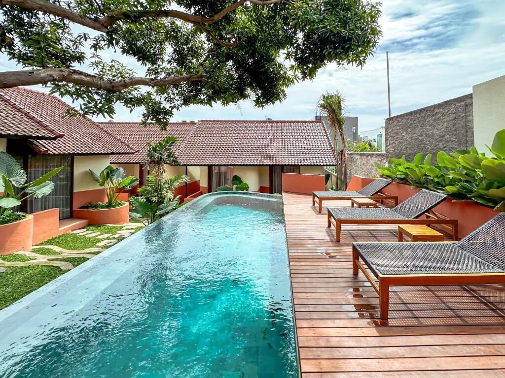 Une piscine avec des chaises longues et des plantes en pot.