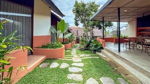 A courtyard with a stone pathway, potted plants, and outdoor seating. - Poh Canggu (Badung)