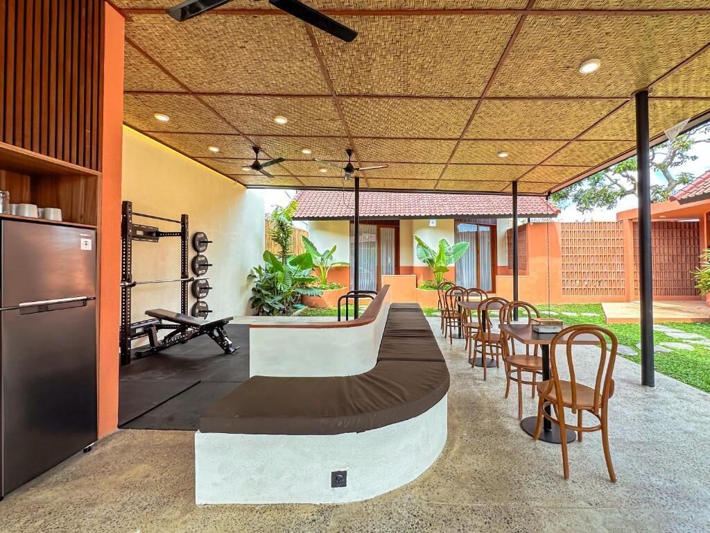 Un espace de remise en forme comprenant un coin pour la musculation, un banc incurvé et des sièges à l’extérieur.
