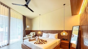 A hotel room with a large bed, a ceiling fan, a nightstand, a lamp, and a view of the outdoors. - Poh Canggu (Badung)