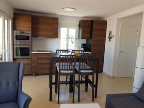 Eine moderne Küche mit Holzschränken, einem Esstisch mit vier Stühlen und einem Einbauofen.