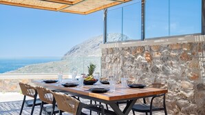 Une table dressée à l’extérieur, offrant une vue sur la mer et les montagnes.