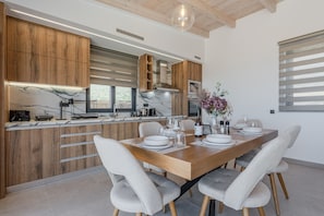 A modern kitchen with wooden cabinets, a marble countertop, and a dining area with a wooden table and chairs.