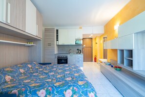 Een moderne slaapkamer met een groot bed, een kitchenette en een badkamer.