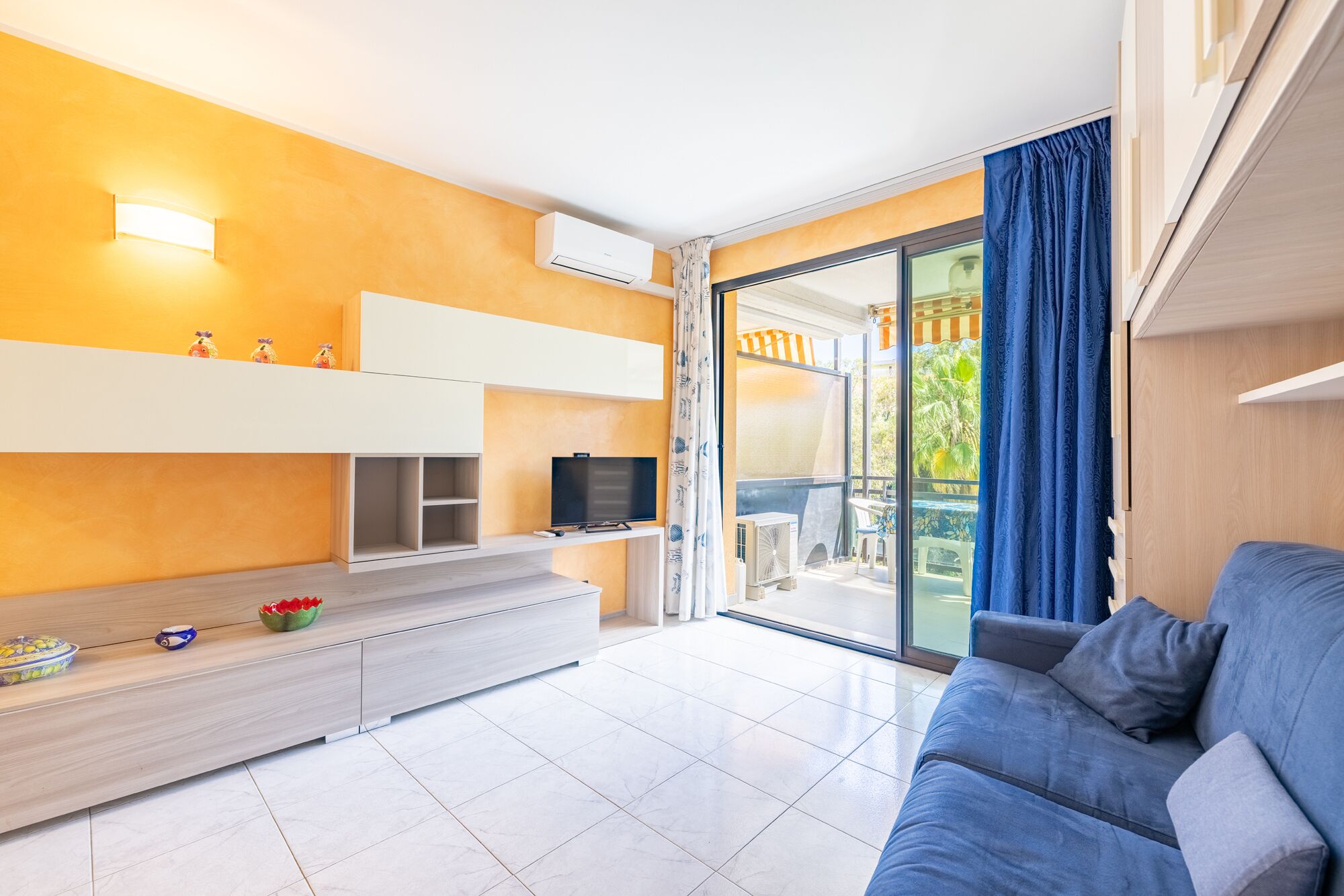 Sala moderna com sofá, televisão e varanda com vista.