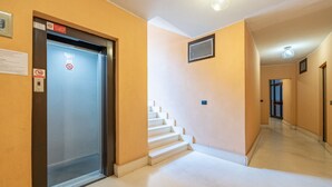 Un pasillo con un ascensor, una escalera y una puerta que da a otra habitación.