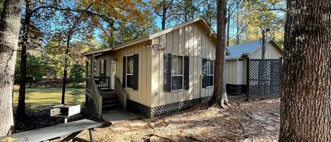 A small cabin with a porch, a picnic table, and a sign indicating the number 22-B.
