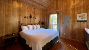 Una stanza con rivestimento in legno, un letto grande, un comodino e un lampadario a parete.