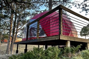 Eine Holzterrasse mit überdachtem Bereich, umgeben von Bäumen und Sträuchern.