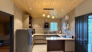 Et moderne køkken med træloft, rustfrie hårde hvidevarer og hængende lamper.