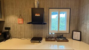 A kitchen with a built-in stove, a range hood, a window with a view of trees, and a sign on the wall.