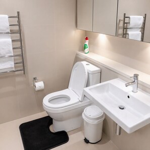 A modern bathroom with a toilet, sink, and towel rack. - Stylish Apartment Sydney Olympic Park Free parking (Sydney Olympic Park)
