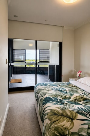 A bedroom with a bed, a view of the balcony, and a door leading to the balcony. - Stylish Apartment Sydney Olympic Park Free parking (Sydney Olympic Park)