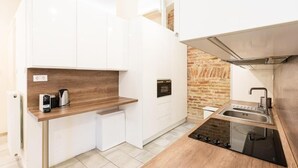 A compact kitchen with white cabinets, a built-in oven, a coffee maker, and a stainless steel sink. - Spacious Luxury apartment at the heart of Budapest (Budapest)