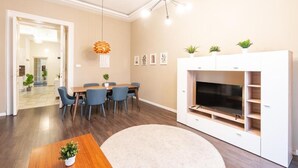 A modern living room with a dining area, a white entertainment unit, and a ceiling fan. - Spacious Luxury apartment at the heart of Budapest (Budapest)