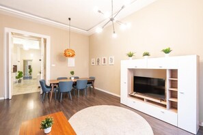 Een moderne woonkamer met een eethoek, een witte televisiemeubel en een plafondventilator.