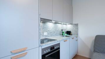 A compact kitchen with white cabinets, a built-in oven, and a granite countertop.