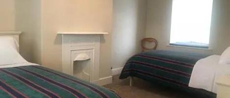 Un dormitorio con dos camas, una chimenea y una ventana.
