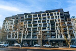 A multi-story building with a modern architectural design, featuring balconies and large windows. - Rooftop Infinity Pool & Bay Views (St Kilda)