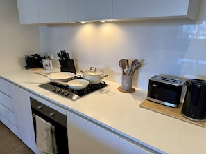 A modern kitchen with a gas stove, pots, a toaster, and a coffee maker. - Rooftop Infinity Pool & Bay Views (St Kilda)