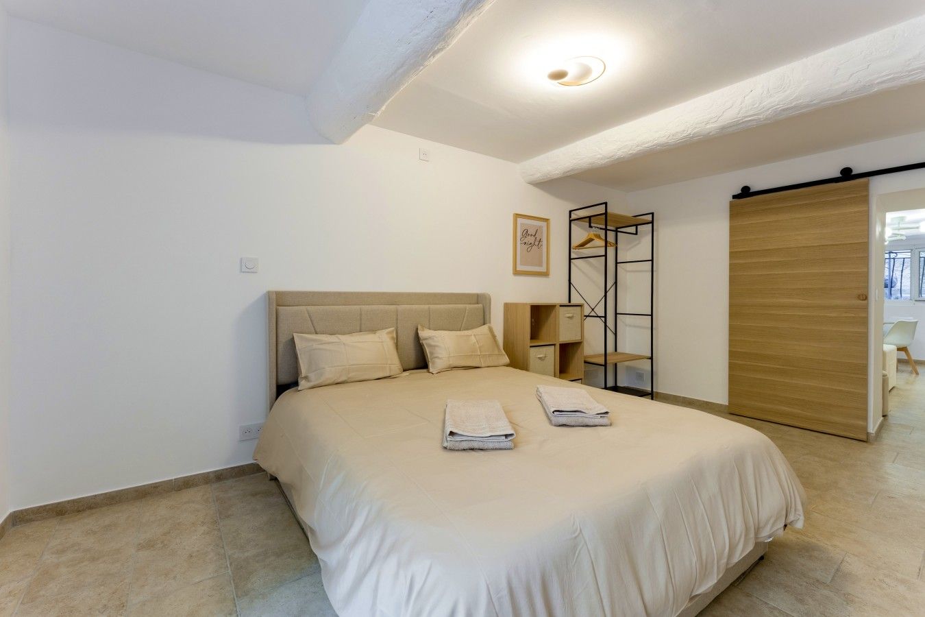 A bedroom with a bed, bedside tables, a wardrobe, and a view of the outside.