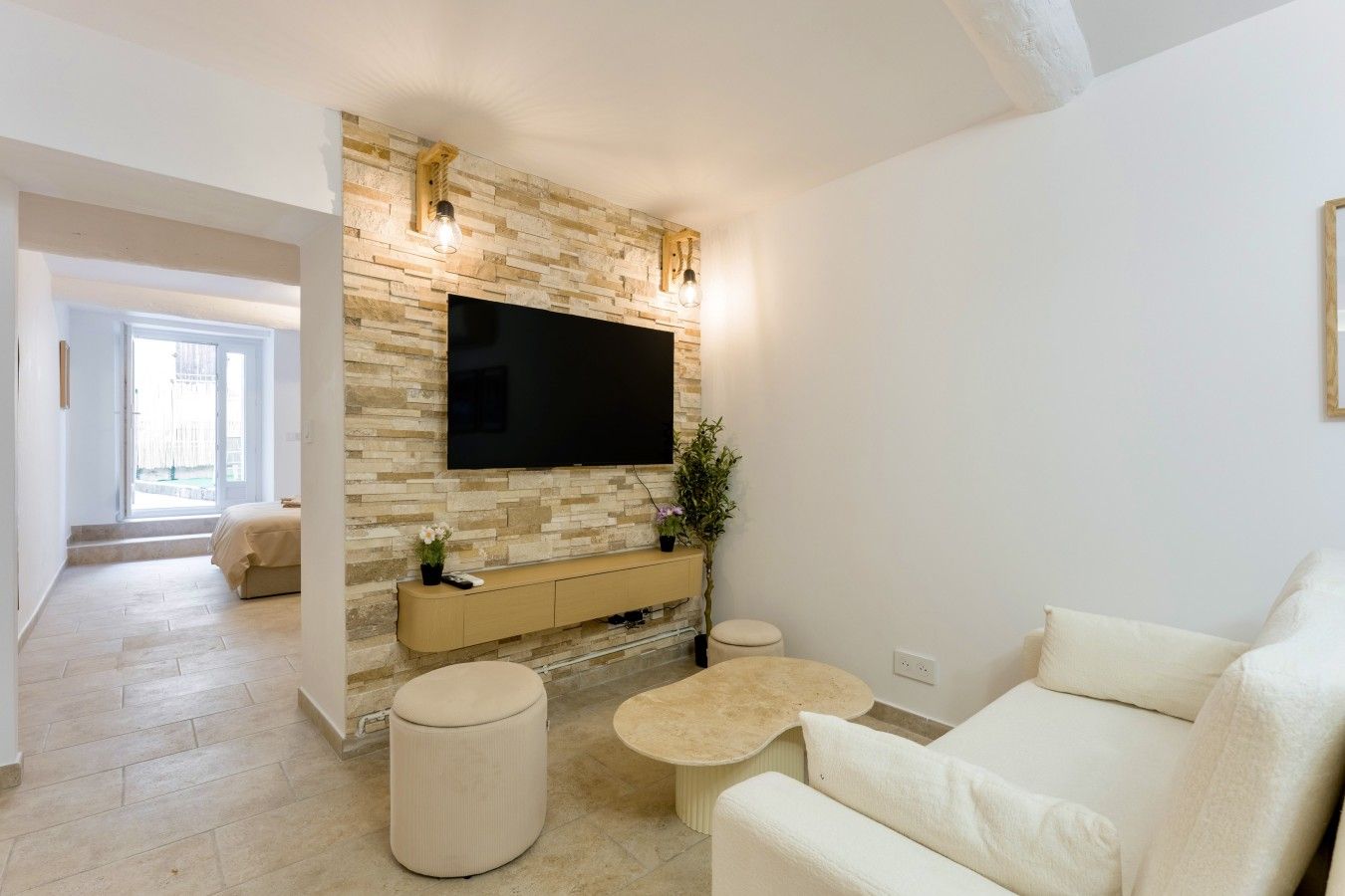 A modern living room with a stone wall, a flat-screen TV, a sofa, and a coffee table.