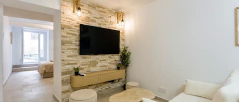 A modern living room with a stone wall, a flat-screen TV, a sofa, and a coffee table.