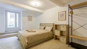 Un dormitorio con cama, mesita de noche, armario y ventana.