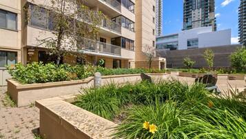 Un edificio residencial de varios pisos con balcones, un patio con plantas y un estilo arquitectónico moderno.